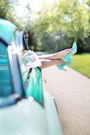 female legs in turquoise shoes stick out of the car window