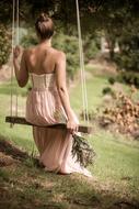 back view of woman in long gown on swing outdoor