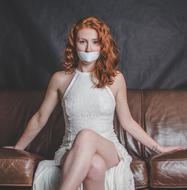photo of red-haired girl in a white dress in her mouth closed