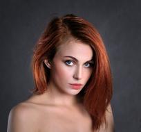 Portrait of the woman with the red hair and blue eyes on grey background