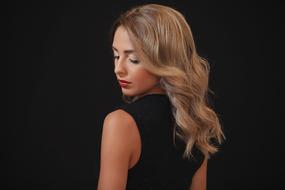 photo of a blonde in a black dress with curly hair