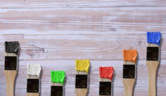Brushes covered with paint on wooden surface