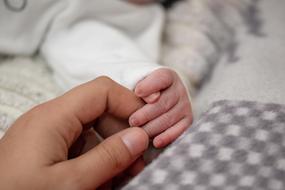 adult person touching Newborn Babyâs Hand