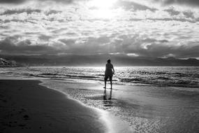 a girl walks along the beach at dusk