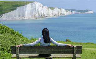 girl sitting on a bench on a background of white cliffs on the ocean
