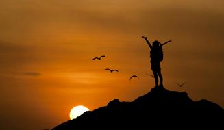 silhouette of a girl on top of a cliff at dusk