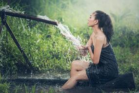 Beautiful Asian woman, having shower, among the green plants in Thailand
