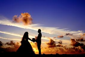 dark silhouettes of groom with bride at sunset