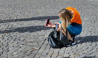 young girl taking Selfie on cobblestone pavement