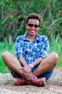 dark skin girl sits on a background of green plants