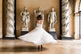 dance of a girl in white in a hall with statues