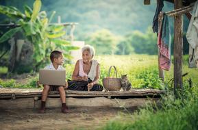 grandmother and grandson with laptop in nature