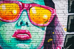 graffiti on the wall in the form of a woman's face in sunglasses