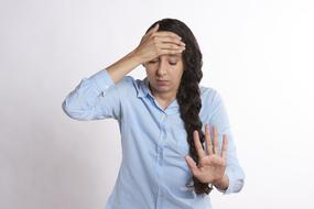 Portrait of young woman with hand on forehead because of stress