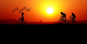 Silhouettes of the cyclists, singing white riding on landscape at colorful sunset background