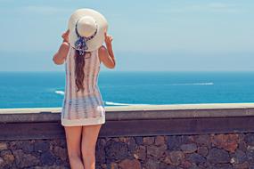 back view of Young Woman in wide hat in front of sea