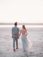 Back view of the couple, walking on the beautiful seaside, under the colorful sky