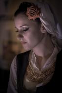 Profile portrait of a woman with closed eyes and in colorful, traditional clothes in Greece