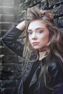 long haired caucasian Girl in black clothe posing at stone wall