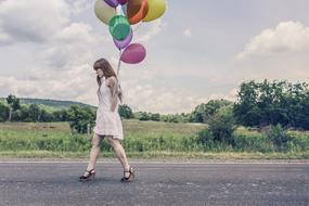 Girl walking on the road with the balloons