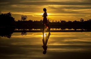 woman walking on coastline at dawn