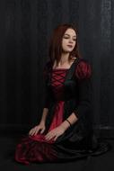 Young Girl in black and red clothe sits in darkness