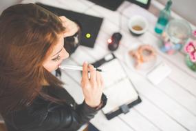 Young Girl with pen at table, top view