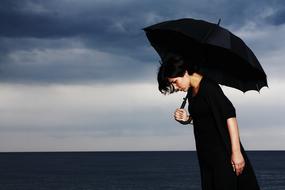 Woman with the black umbrella near the water