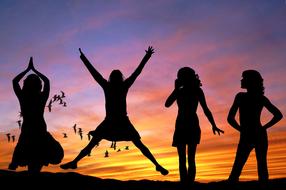 silhouettes of happy girls at sunset