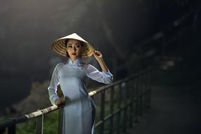 beautiful Asian Lady in traditional straw hat posing on bridge