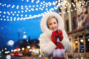 Woman in winter clothe posing in front of Christmas Lights in city