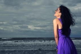 girl in a purple dress on the beach in a storm