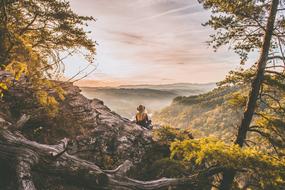 woman sits on mountain side at scenic misty autumn Landscape