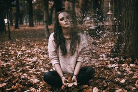 Sadness, Depressed Woman sits on fallen leaves in park