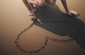 woman drawing on sea sand beach