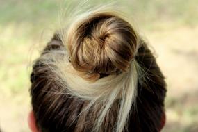 Close-up of the beautiful, blonde and dork hairstyle on the head of a woman, at blurred background