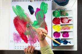 child draws watercolors on a calendar