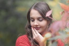 Portrait of the woman near the colorful flowers, at blurred background in autumn