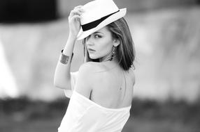 Black and white photo of the beautiful girl with the accessories, posing with the hat