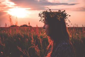 Profile portrait of the girl, with the colorful and beautiful flower chaplet, on the colorful and beautiful field, at colorful and beautiful sunset