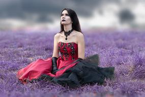 young Woman in Gothic Dress sits on purple grass