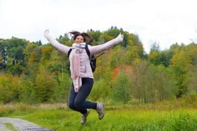 Smiling woman, jumping, on the path, among the colorful and beautiful plants