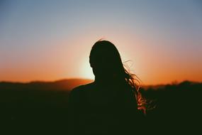 Silhouette of a woman on the landscape at beautiful and colorful sunset in the evening