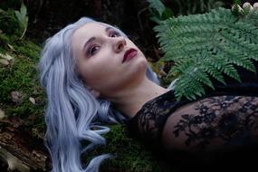 grey haired young Woman lays on moss in Forest, Portrait