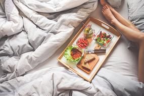 breakfast on a tray and the girl's legs on the bed