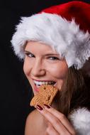happy Woman in santa hat with cookie at lips