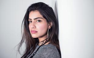 Portrait of the beautiful woman with headphones posing near the white wall
