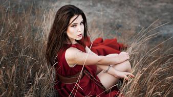 young Lovely Woman in red dress sits on grass