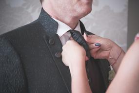 woman helping with tie to man