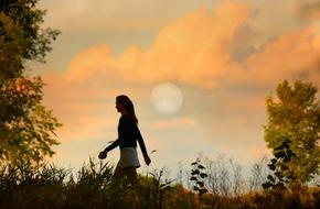 Woman Walking through grass at dusk